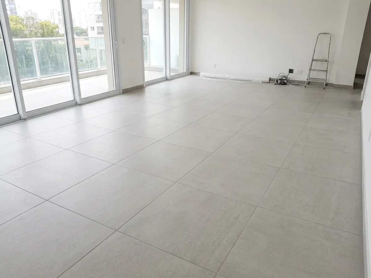 Piso de sala com porcelanato cinza claro instalado em paginação alinhada com juntas retas ortogonais