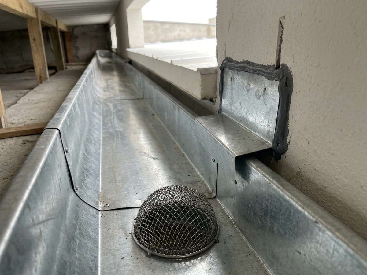 Detalhe de calha embutida de chapa galvanizada e rufo de encosto instalados rente à platibanda de alvenaria